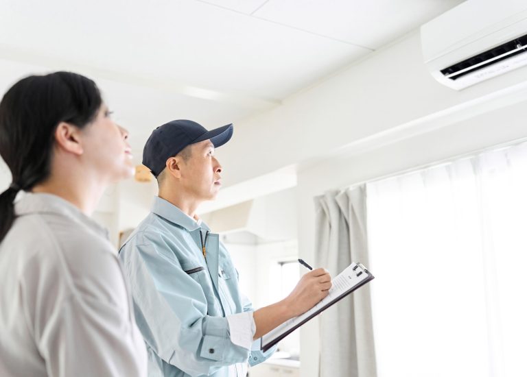 Asian worker inspecting air conditioner